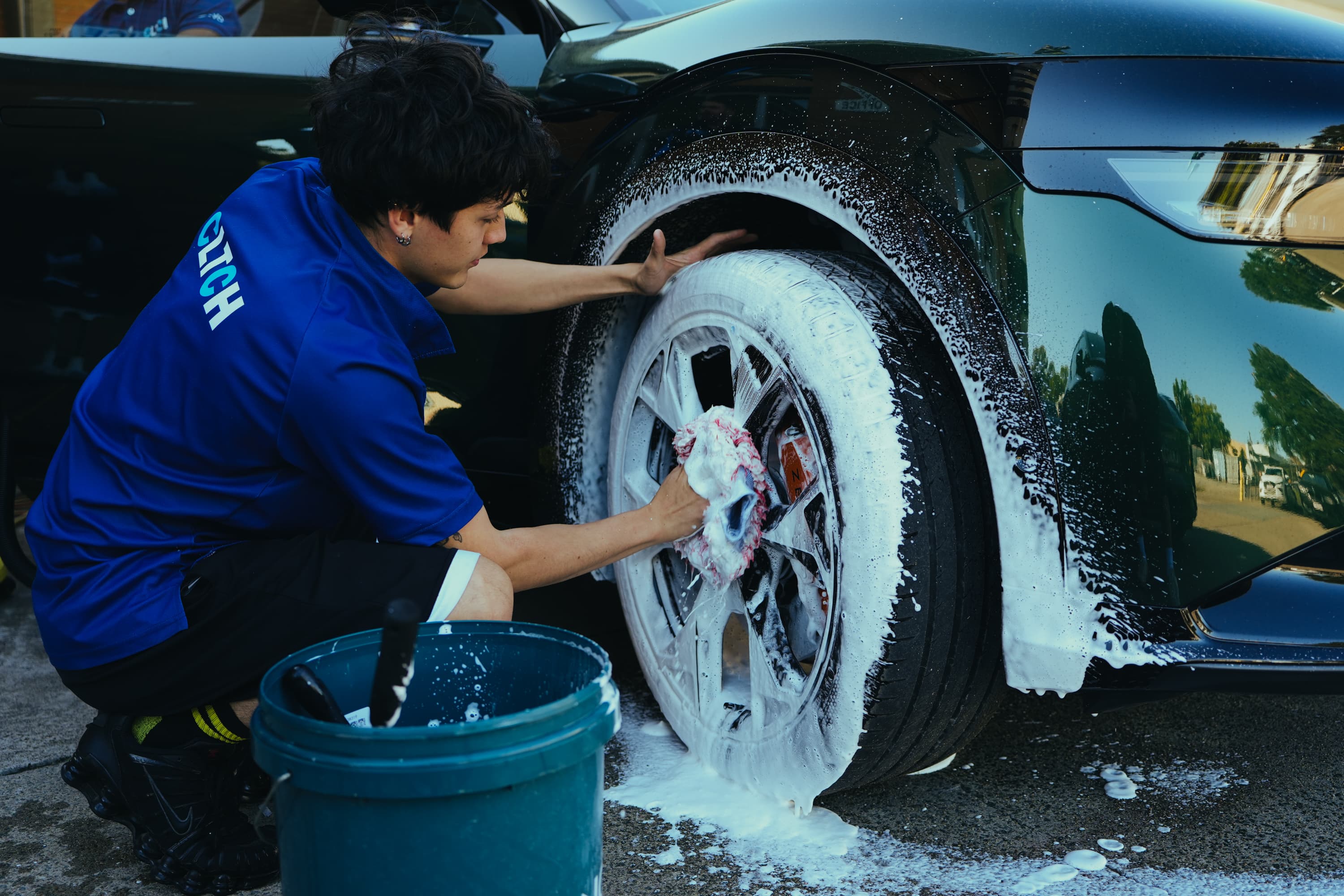 CLTCH detailer foam-washing wheels in a Brisbane driveway